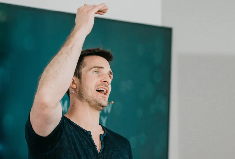 Matthew Hussey speaking with his hand raised in the air