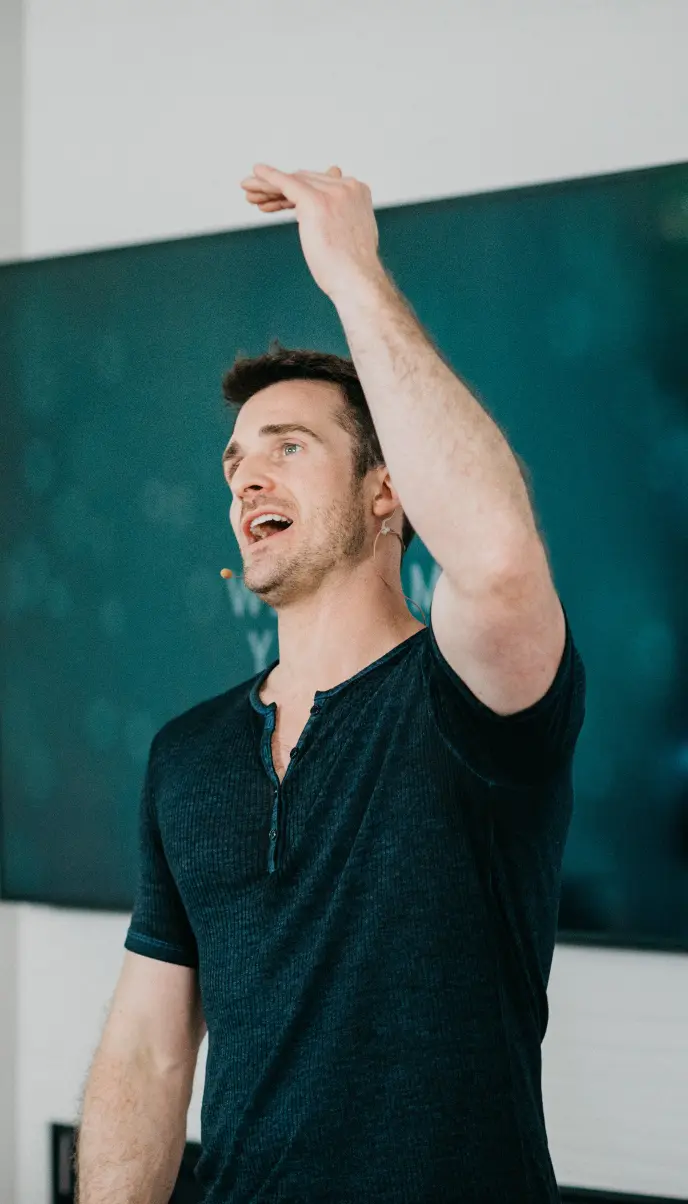 Matthew Hussey speaking with his hand raised in the air